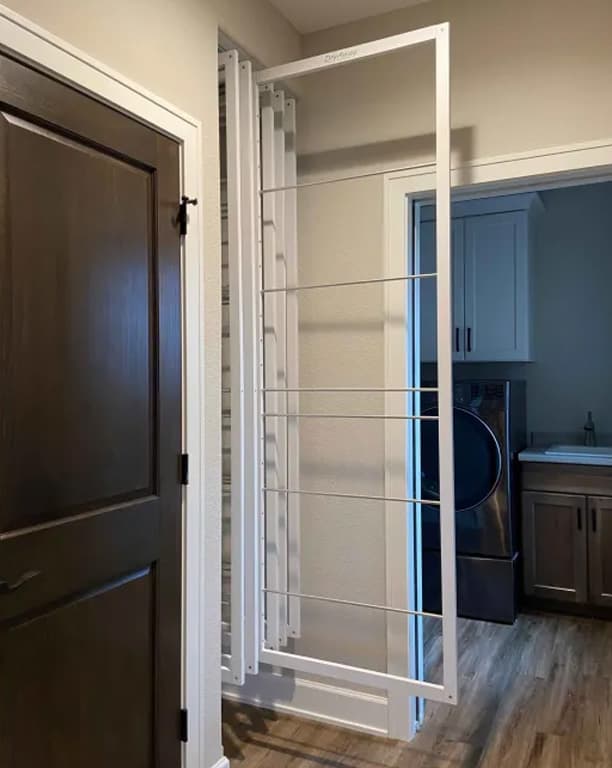 DryAway drying rack folded flat and stored against a hallway wall next to a laundry room