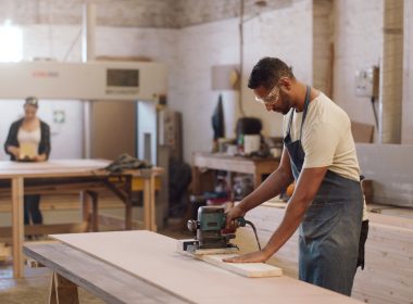 Carpenter man and sanding machine in workshop with woodwork project furniture production and craft Artisan person and manufacturing with glasses electric tools or carpentry equipment for timber