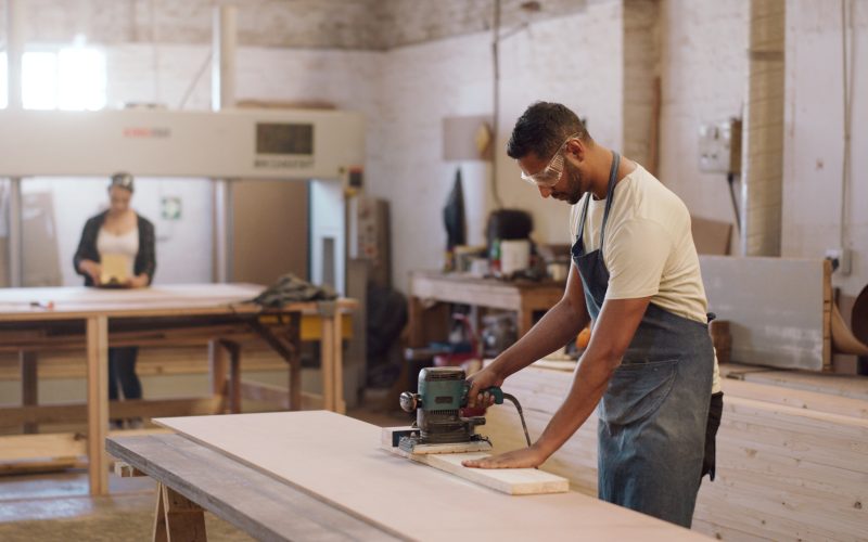 Carpenter man and sanding machine in workshop with woodwork project furniture production and craft Artisan person and manufacturing with glasses electric tools or carpentry equipment for timber