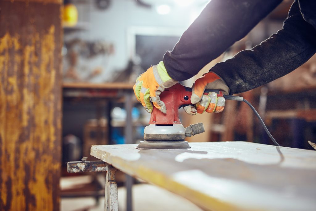 Carpenter using orbital electric sander in a retro vintage works - Wurth Louis and Company Carpenter using orbital electric sander in a retro vintage works