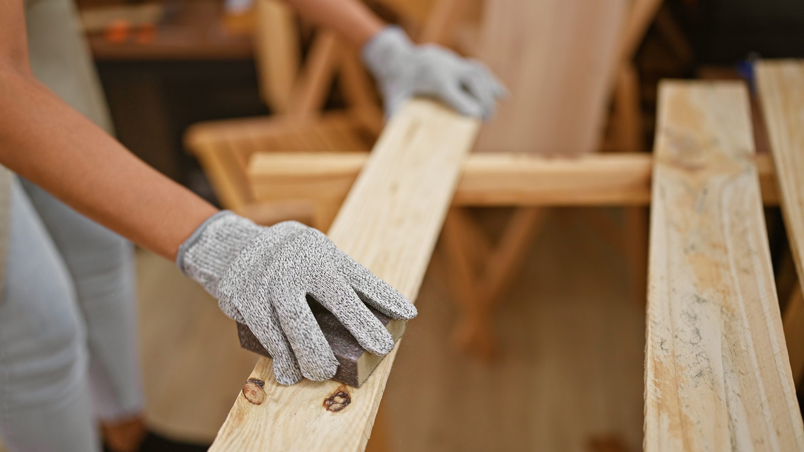 Hispanic woman carpenter at work sanding wood plank with her hands at indoor carpentry workshop - Wurth Louis and Company Hispanic woman carpenter at work sanding wood plank with her hands at indoor carpentry workshop