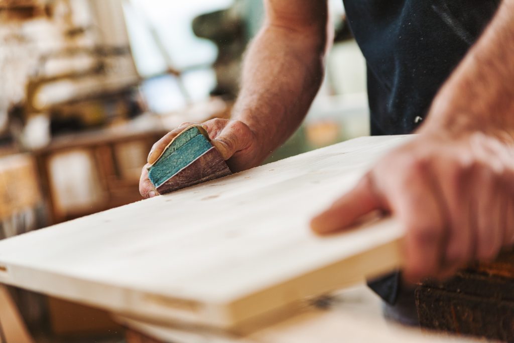 Carpenter sanding wood using sandpaper in workshop - Wurth Louis and Company Carpenter sanding wood using sandpaper in workshop